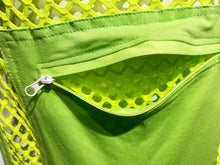 Load image into Gallery viewer, Close up view of neon green fishnet overalls, focusing on the kangaroo pocket with zipper undone.