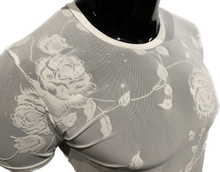 Load image into Gallery viewer, Close up view of a white mesh fabric t-shirt with a flocked rose and leaves pattern, displayed on a mannequin.