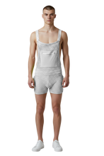 Load image into Gallery viewer, Model wearing a pair of white overalls made from a fishnet fabric, featuring button straps, side pockets, and a zipper kangaroo pocket