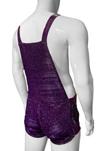 Load image into Gallery viewer, Rear view of mannequin wearing purple glitter overalls with button straps, side pockets, and zipper kangaroo pocket