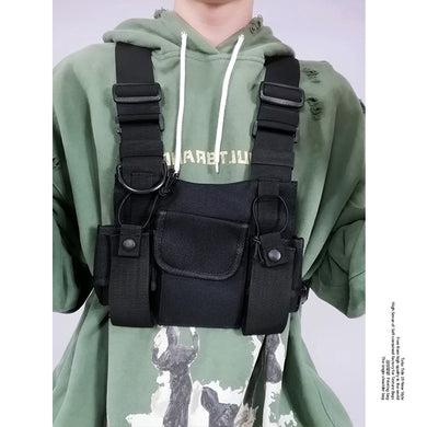 Person wearing a green hoodie with a tactical chest bag over it