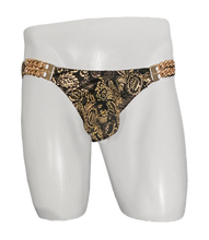 Load image into Gallery viewer, Gold and black patterned swim brief displayed on a white mannequin torso. Gold-colored chains on each side.
