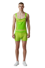 Load image into Gallery viewer, Model wearing a pair of overalls made with a neon green fishnet overalls with button straps, side pockets, and a zipper kangaroo pocket
