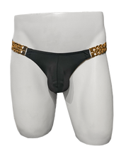 Load image into Gallery viewer, Mannequin wearing black swim brief with gold chains on either side that hold the fabric 
