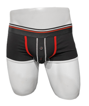 Load image into Gallery viewer, Mannequin wearing black trunk underwear with red trim around the pouch. Pouch has a button fly and the waistband is black with a white stripe and a red stripe.
