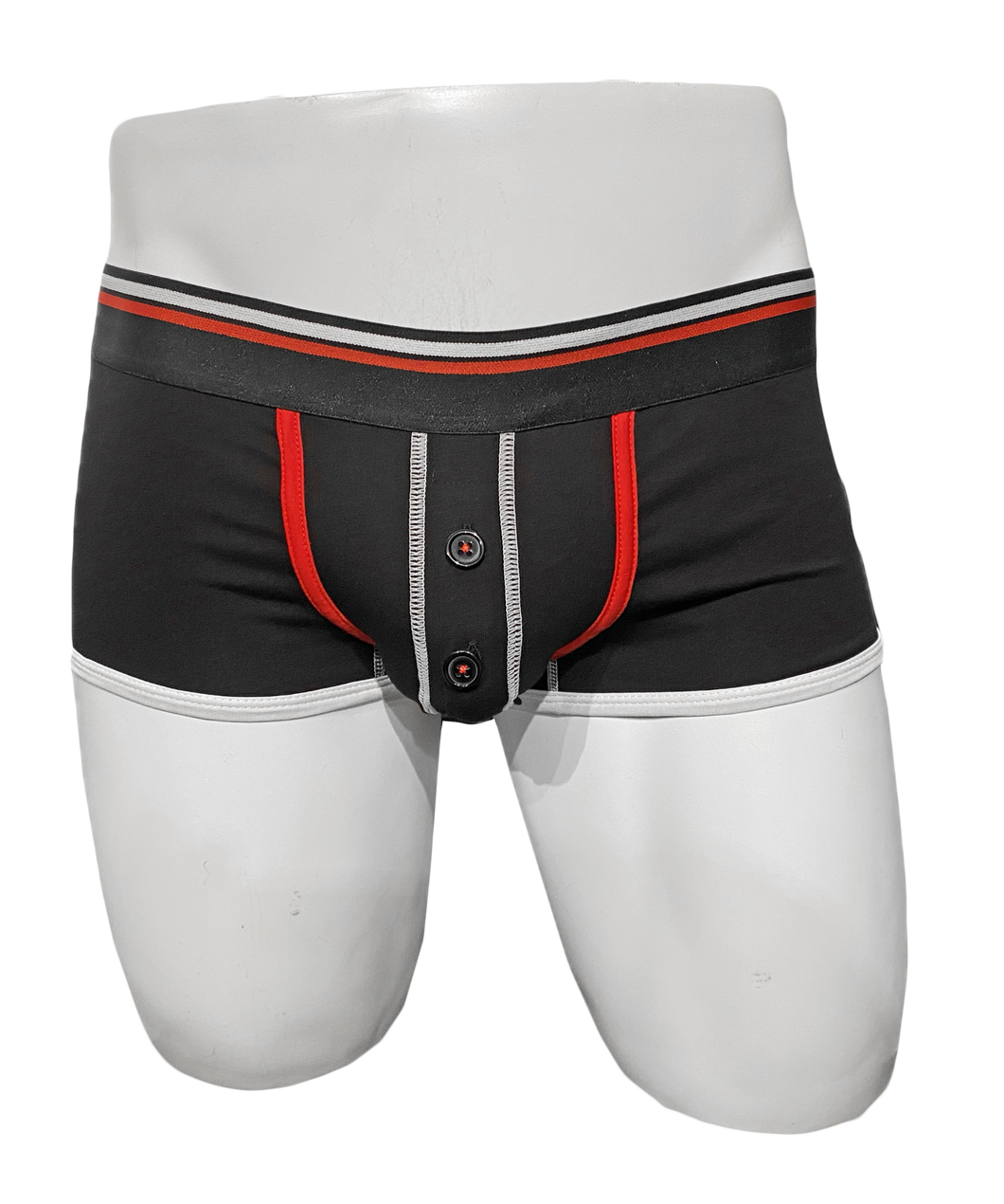Mannequin wearing black trunk underwear with red trim around the pouch. Pouch has a button fly and the waistband is black with a white stripe and a red stripe.