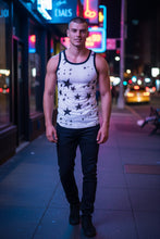 Load image into Gallery viewer, Model wearing a white mesh tank top with printed black stars and black trim, on a street background
