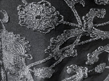 Load image into Gallery viewer, Close-up of a black fabric with raised silver floral embroidery and metallic sheen.
