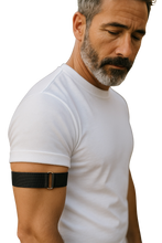 Load image into Gallery viewer, Man wearing a white t-shirt wearing a black arm band 
