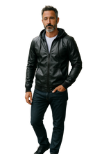 Load image into Gallery viewer, Man wearing a black zip-up faux leather hoodie with black zipper and hood strings. Hand in jean pockets
