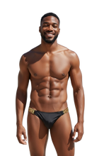Load image into Gallery viewer, Man wearing black swim briefs with gold chains in place of the side waistbands
