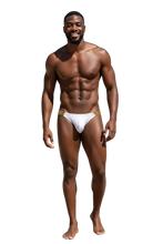 Load image into Gallery viewer, Man wearing a white swim brief with gold chains at the sides that hold the fabric
