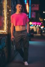 Load image into Gallery viewer, Model wearing hot pink acid wash crop tee while leaning on a building with graffiti on it. 
