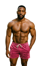 Load image into Gallery viewer, Man wearing hot pink velvet shorts with pockets and a drawstring
